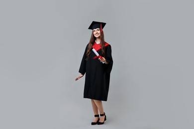 Photo of Happy student with diploma after graduation on grey background