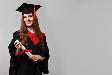 Photo of Happy student with diploma after graduation on grey background. Space for text