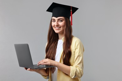 Photo of Happy student with laptop after graduation on grey background