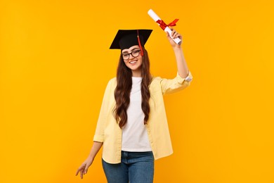 Photo of Happy student with laptop and diploma after graduation on orange background