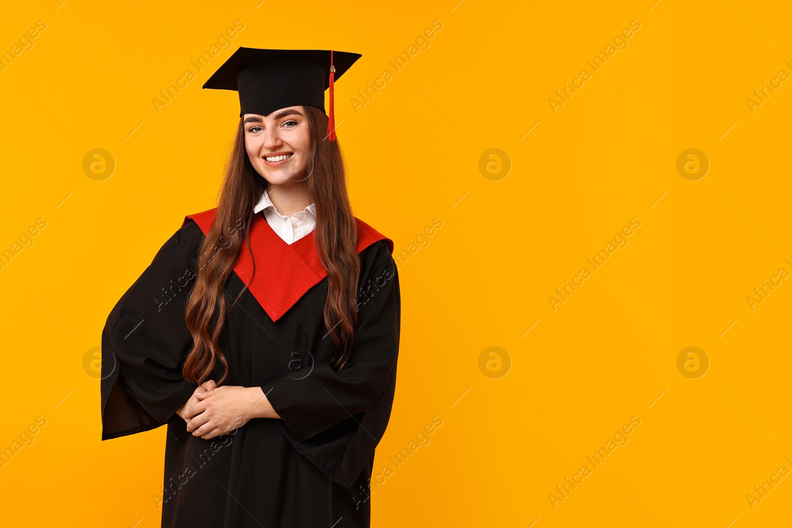 Photo of Happy student after graduation on orange background. Space for text