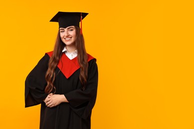 Photo of Happy student after graduation on orange background. Space for text