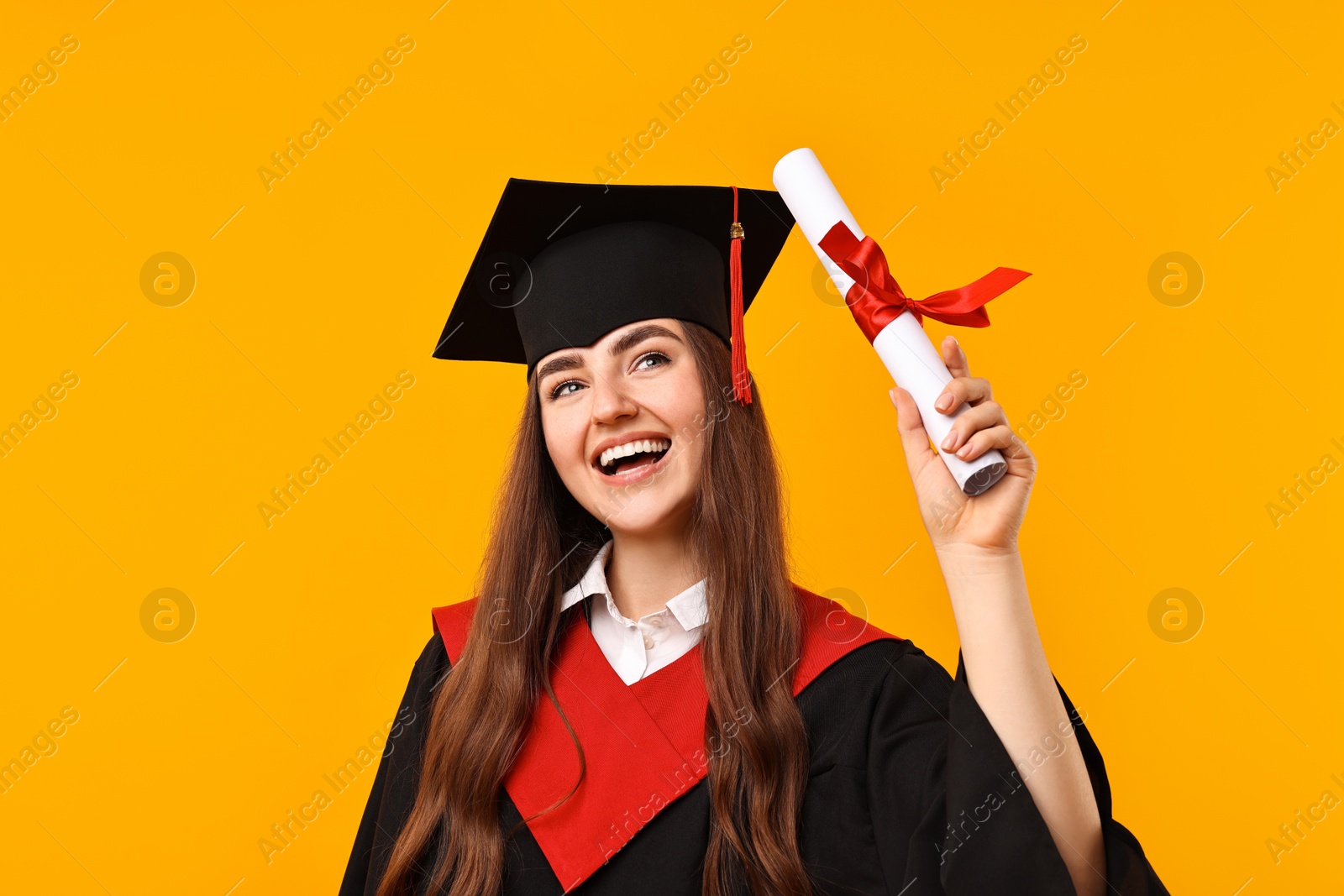 Photo of Happy student with diploma after graduation on orange background