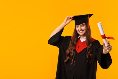 Photo of Happy student with diploma after graduation on orange background. Space for text