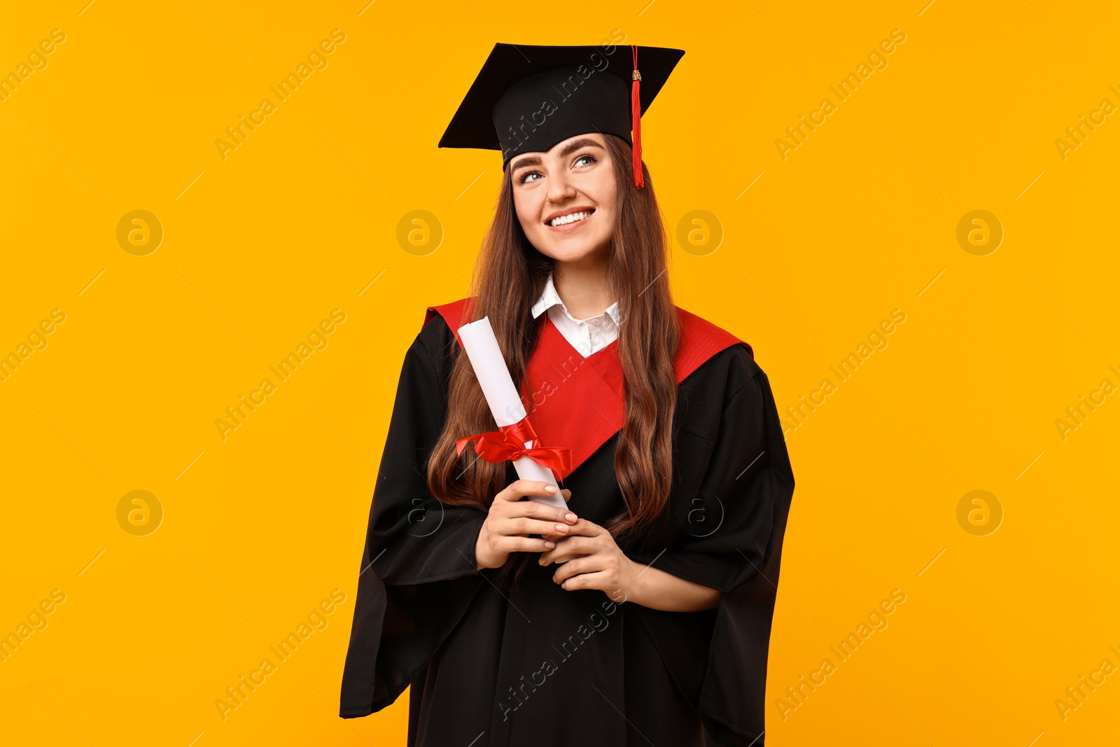 Photo of Happy student with diploma after graduation on orange background