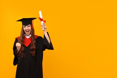 Photo of Happy student with diploma after graduation on orange background. Space for text