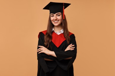 Photo of Happy student with crossed arms after graduation on beige background