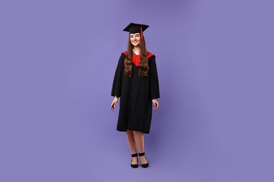 Photo of Happy student after graduation on violet background