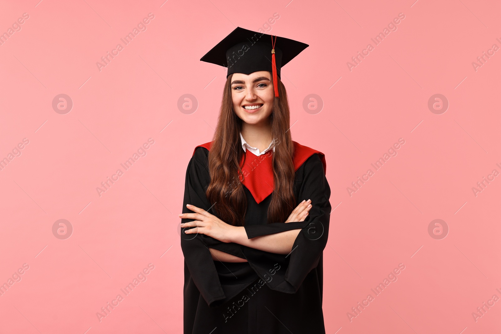 Photo of Happy student with crossed arms after graduation on pink background