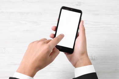 Photo of Man unlocking smartphone with fingerprint scanner at light wooden table, top view