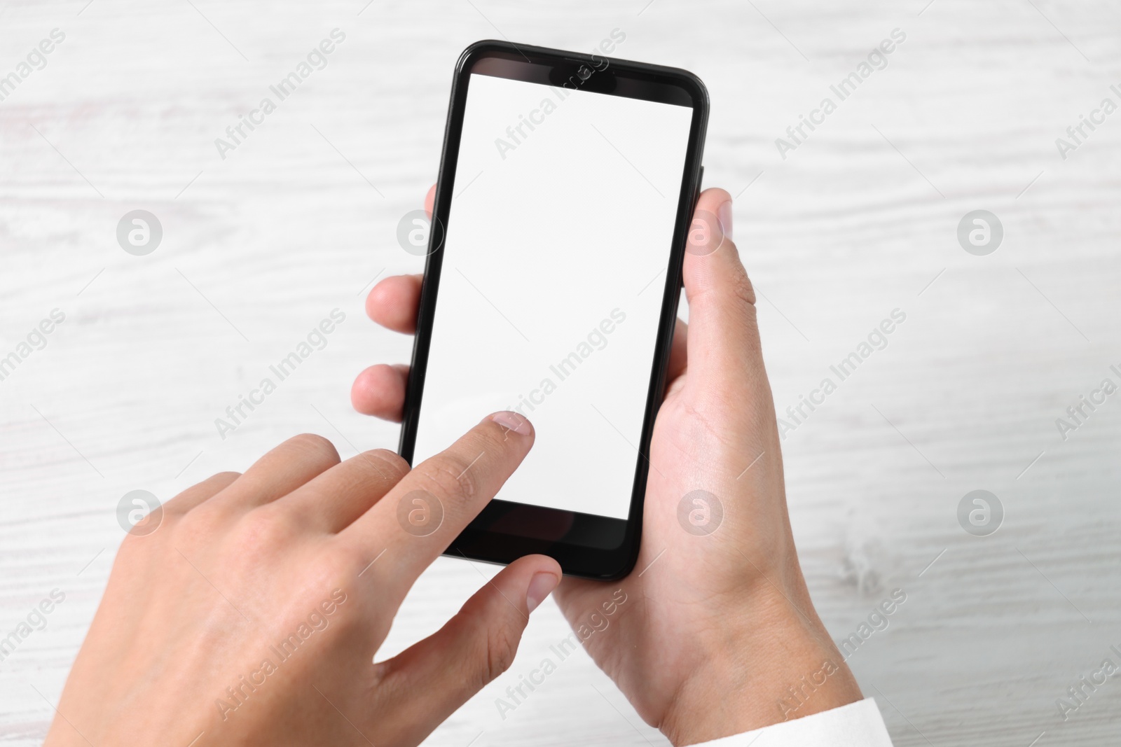 Photo of Man unlocking smartphone with fingerprint scanner at light wooden table, top view