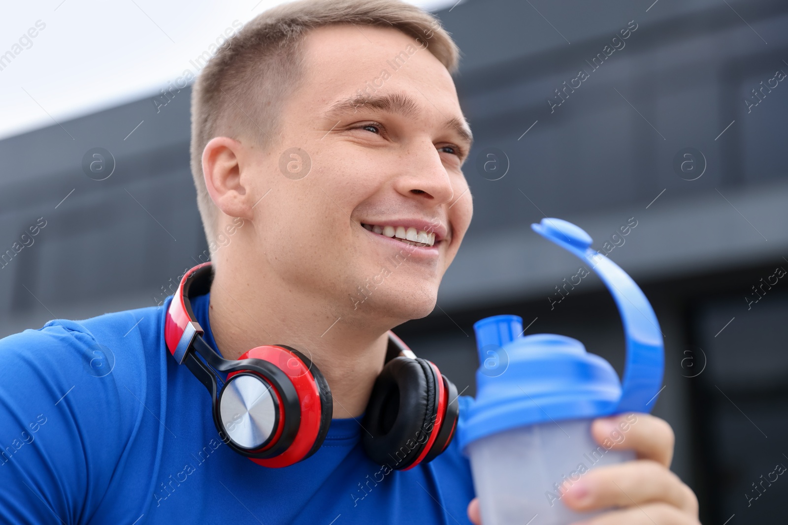 Photo of Smiling man with shaker of protein drink outdoors