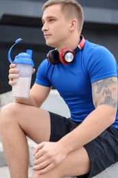 Photo of Athletic man with shaker of protein drink outdoors