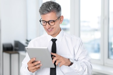 Photo of Businessman with glasses using tablet in office