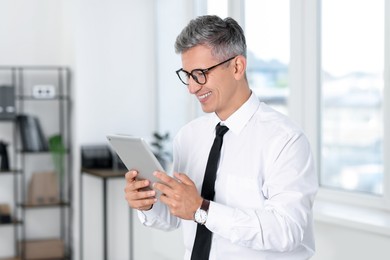 Photo of Businessman with glasses using tablet in office