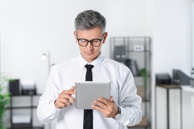 Photo of Businessman with glasses using tablet in office