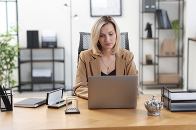 Photo of Businesswoman working on laptop at table in office