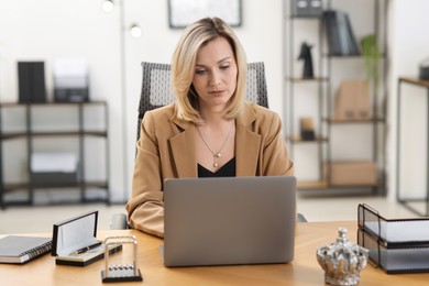 Photo of Businesswoman working on laptop at table in office