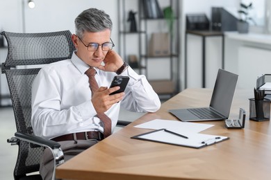 Photo of Businessman using smartphone at table in office