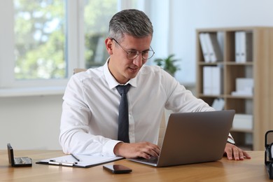 Photo of Businessman working on laptop at table in office