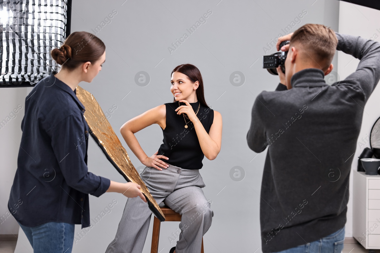 Photo of Photographer and assistant working with model in professional photo studio