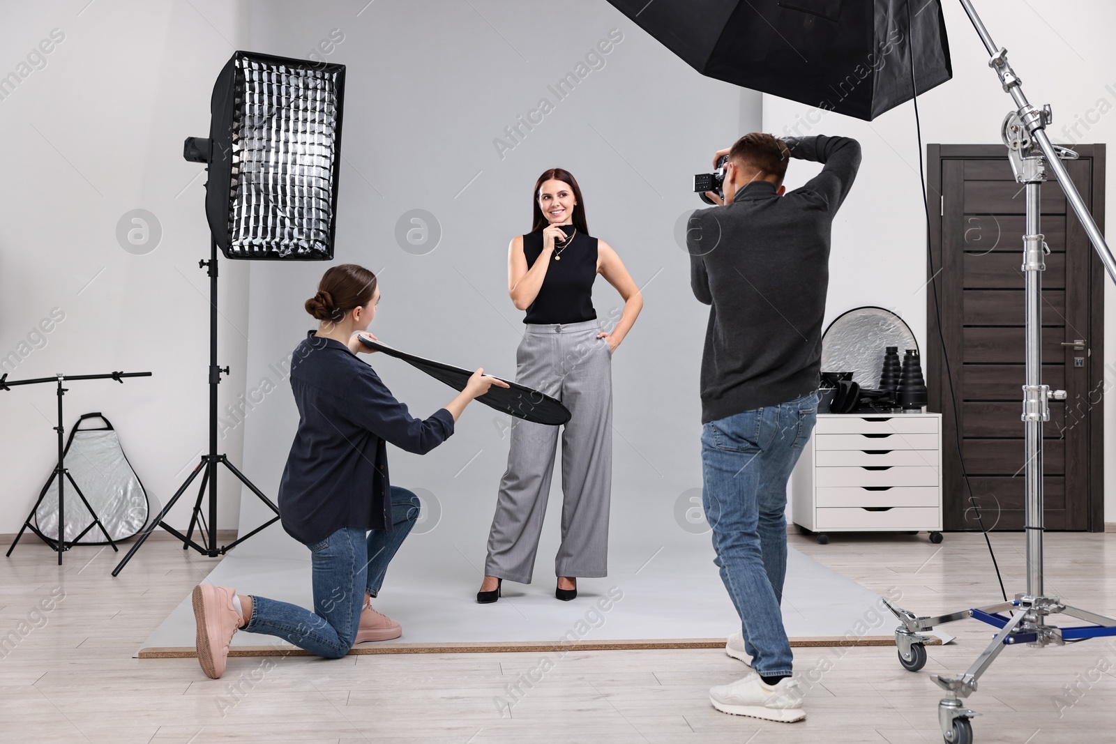 Photo of Photographer and assistant working with model in professional photo studio