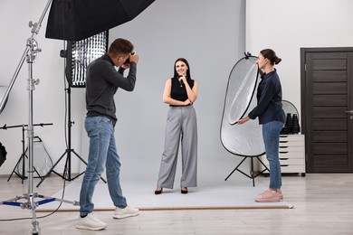 Photo of Photographer and assistant working with model in professional photo studio