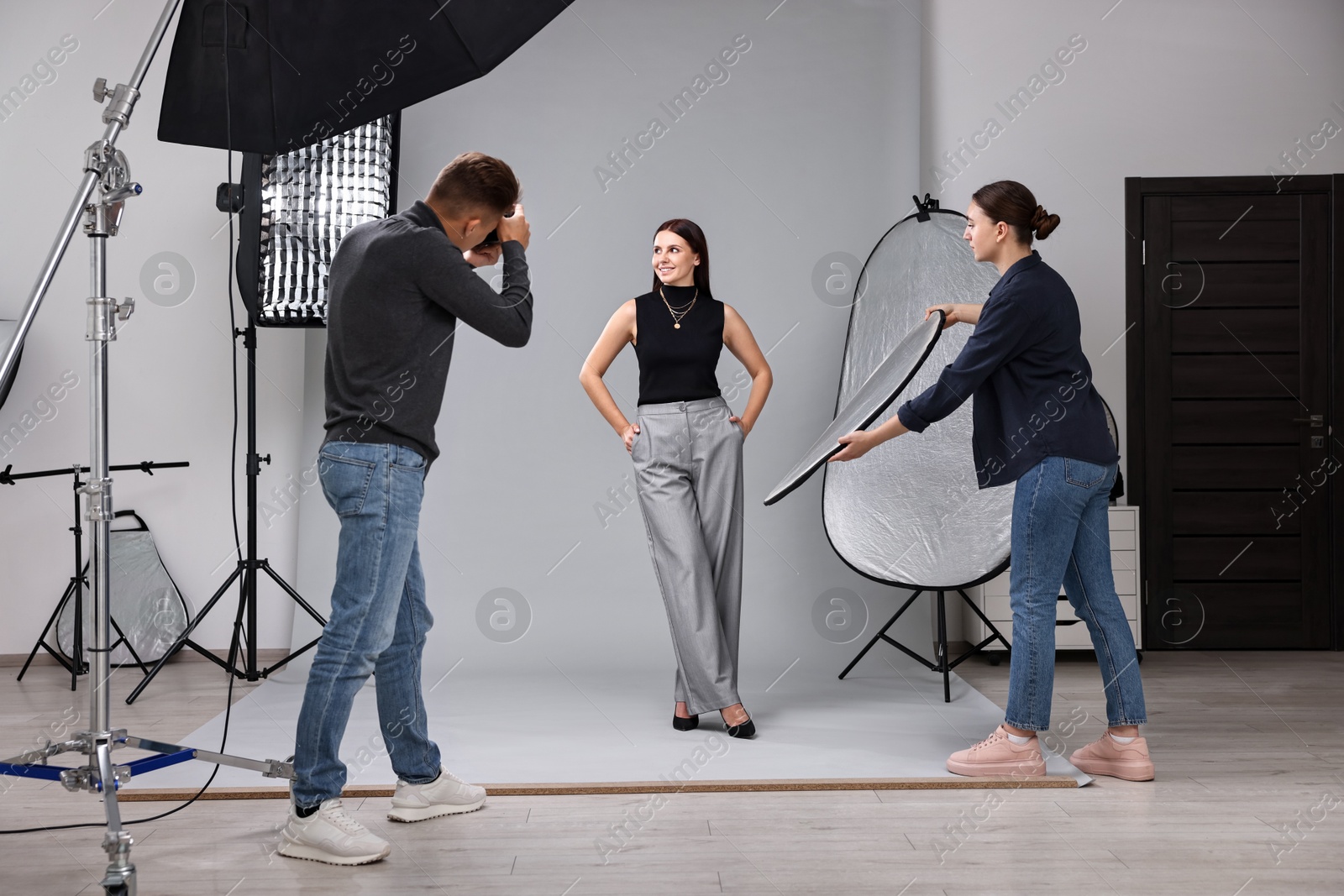 Photo of Photographer and assistant working with model in professional photo studio