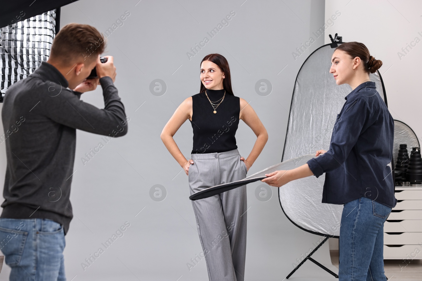 Photo of Photographer and assistant working with model in professional photo studio