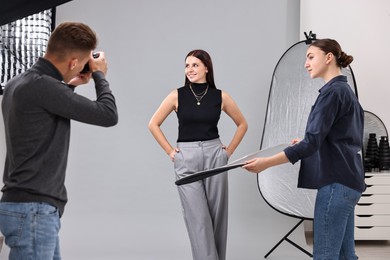 Photo of Photographer and assistant working with model in professional photo studio