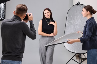 Photo of Photographer and assistant working with model in professional photo studio