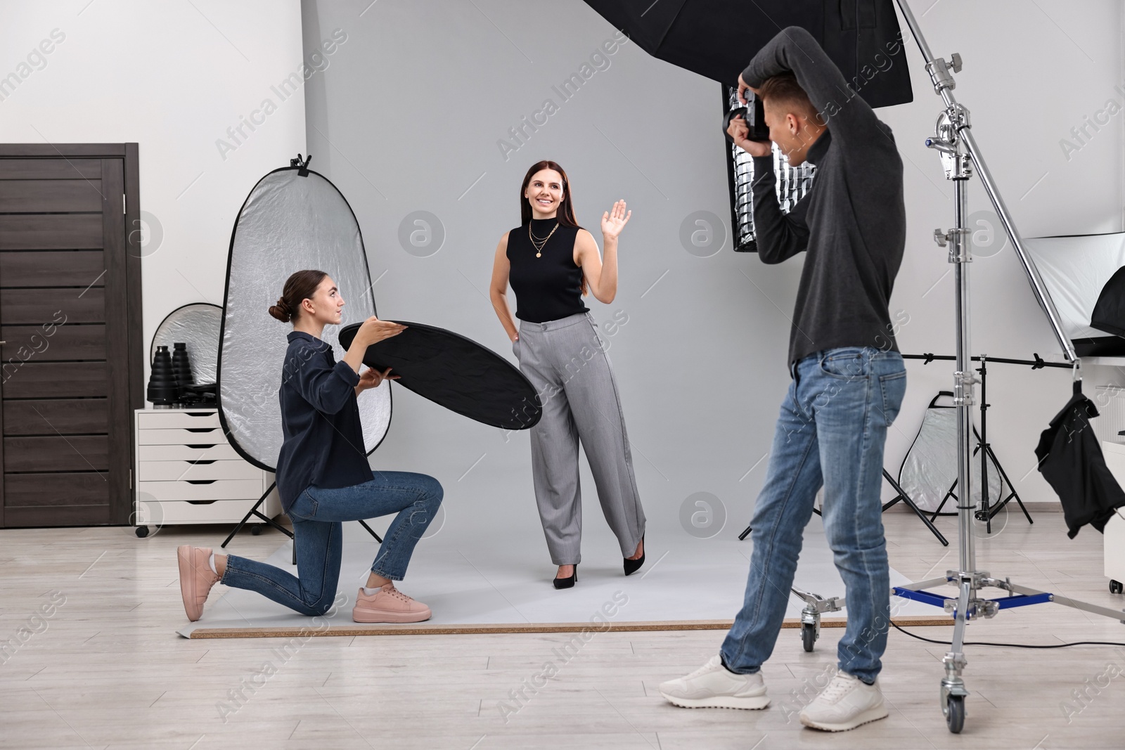 Photo of Photographer and assistant working with model in professional photo studio