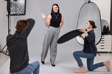 Photo of Photographer and assistant working with model in professional photo studio