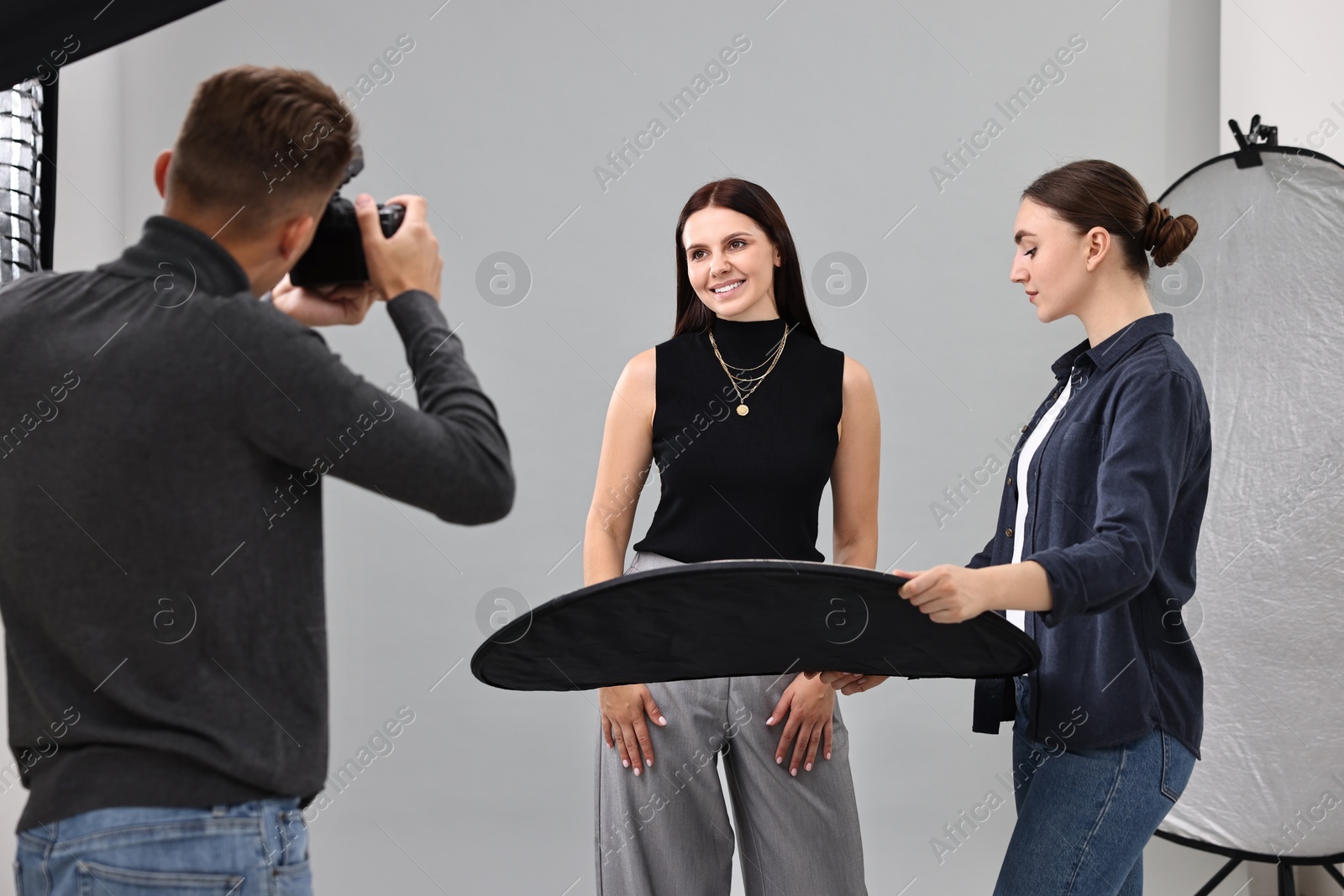 Photo of Photographer and assistant working with model in professional photo studio