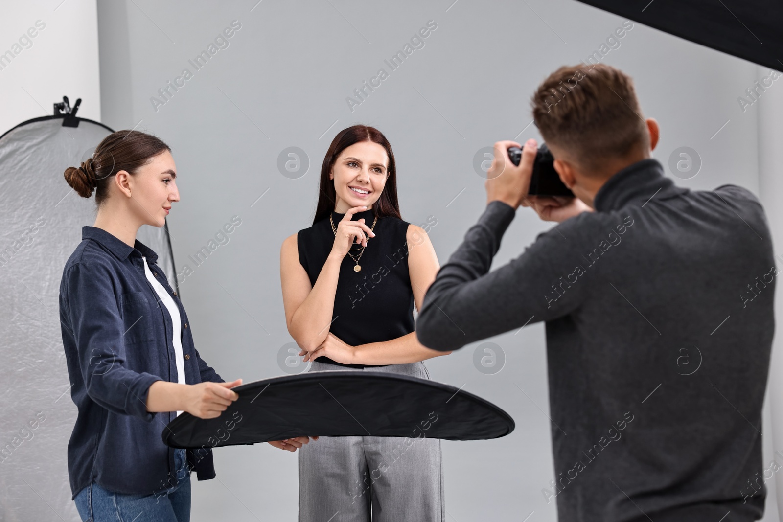 Photo of Photographer and assistant working with model in professional photo studio