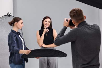 Photo of Photographer and assistant working with model in professional photo studio