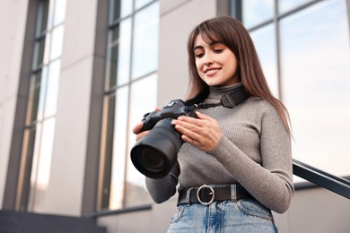 Photo of Professional photographer with digital camera outdoors, low angle view. Space for text