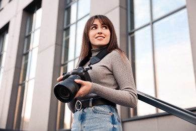 Photo of Professional photographer with digital camera outdoors, low angle view