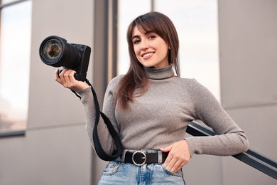 Professional photographer with digital camera near building outdoors