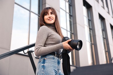 Photo of Professional photographer with digital camera outdoors, low angle view