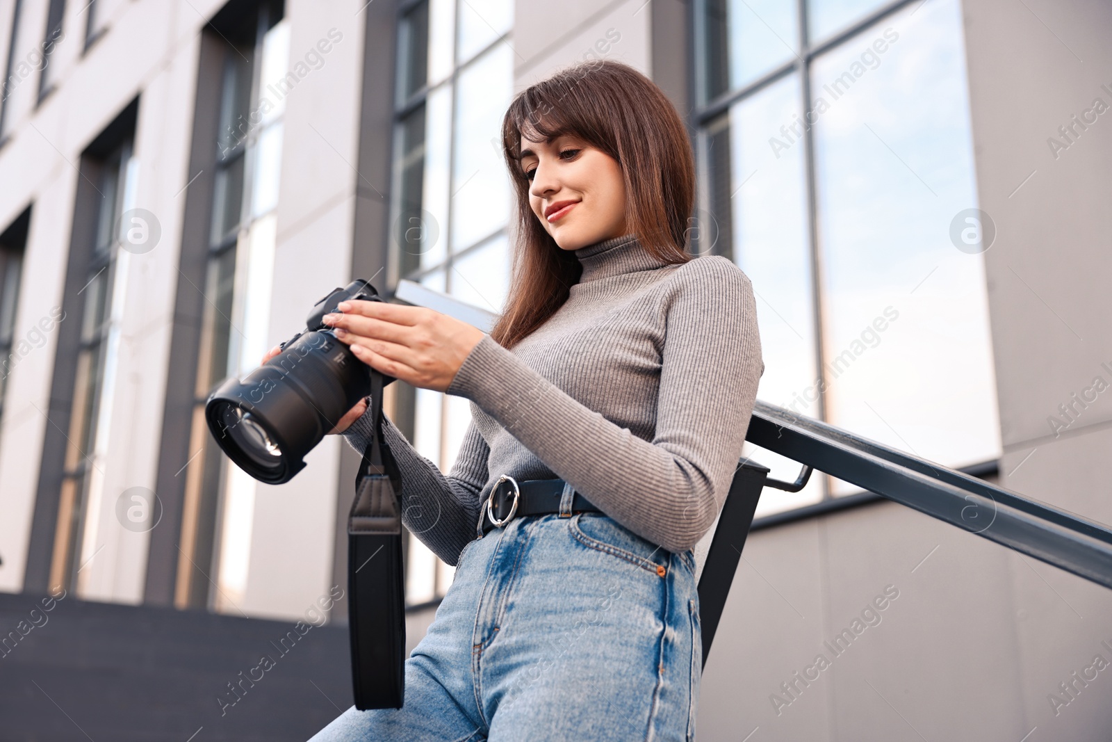 Photo of Professional photographer with digital camera outdoors, low angle view