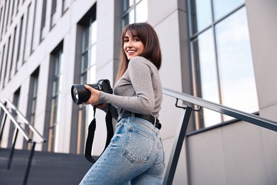 Photo of Professional photographer with digital camera outdoors, low angle view