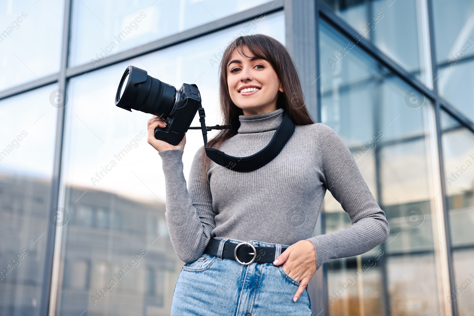 Photo of Professional photographer with digital camera outdoors, low angle view