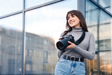 Photo of Professional photographer with digital camera outdoors, low angle view. Space for text