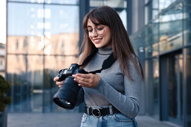 Professional photographer with digital camera near building outdoors