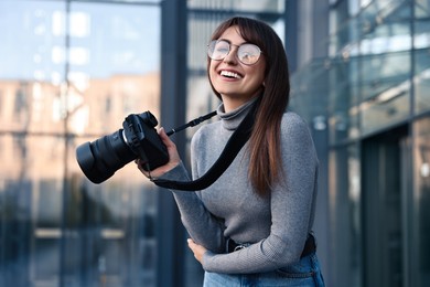 Professional photographer with digital camera near building outdoors