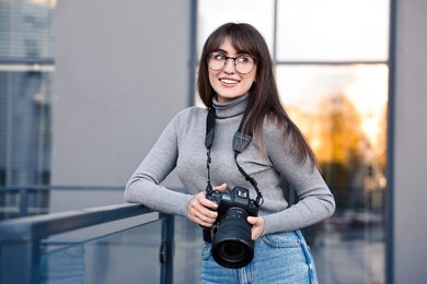 Professional photographer with digital camera near building outdoors