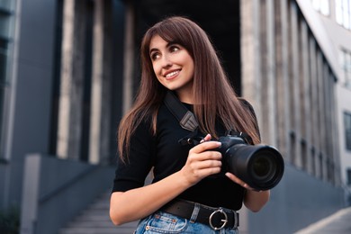 Professional photographer with digital camera near building outdoors