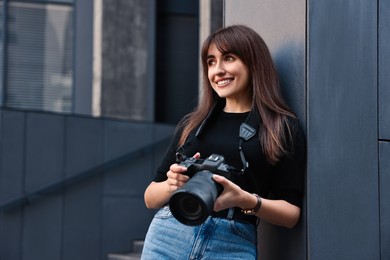 Photo of Professional photographer with digital camera near building outdoors. Space for text