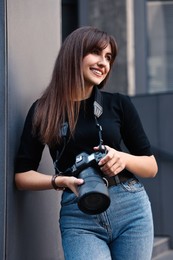 Professional photographer with digital camera near building outdoors